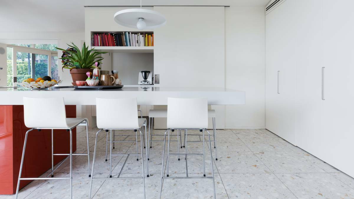 Clean crisp white modern kitchen island bench with high chairs and terrazzo floor